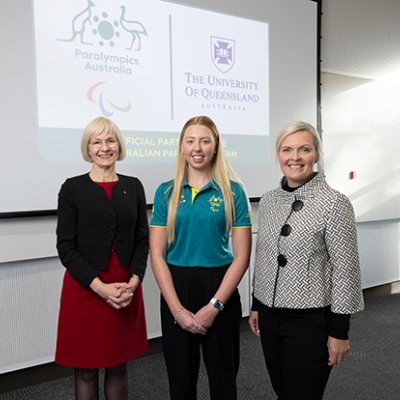 Three women standing in front of a screen displaying corporate logos